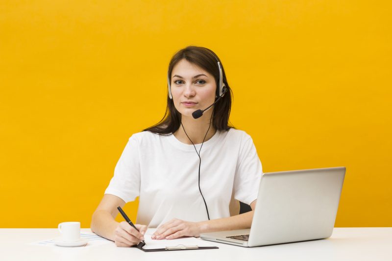 front-view-woman-posing-her-desk-while-wearing-headset